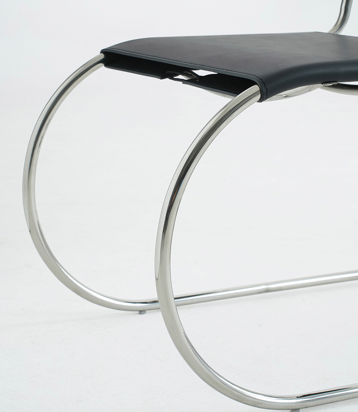 Close-up of a modern chair with a black seat cushion and a curved polished metal frame on a white background.