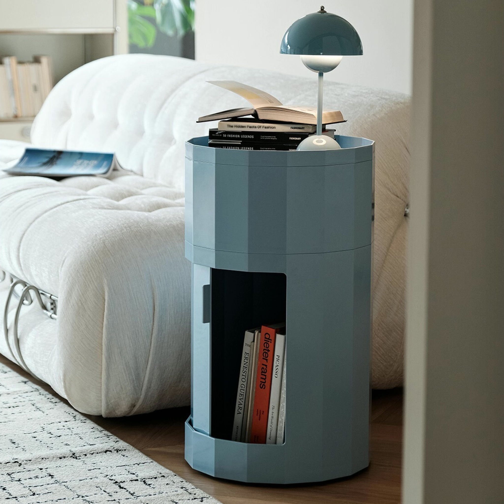 Hex_Plastic_Storage_Unit_Active_thefeelter_Australia- Blue cylindrical side table with books and a lamp in a living room setting.