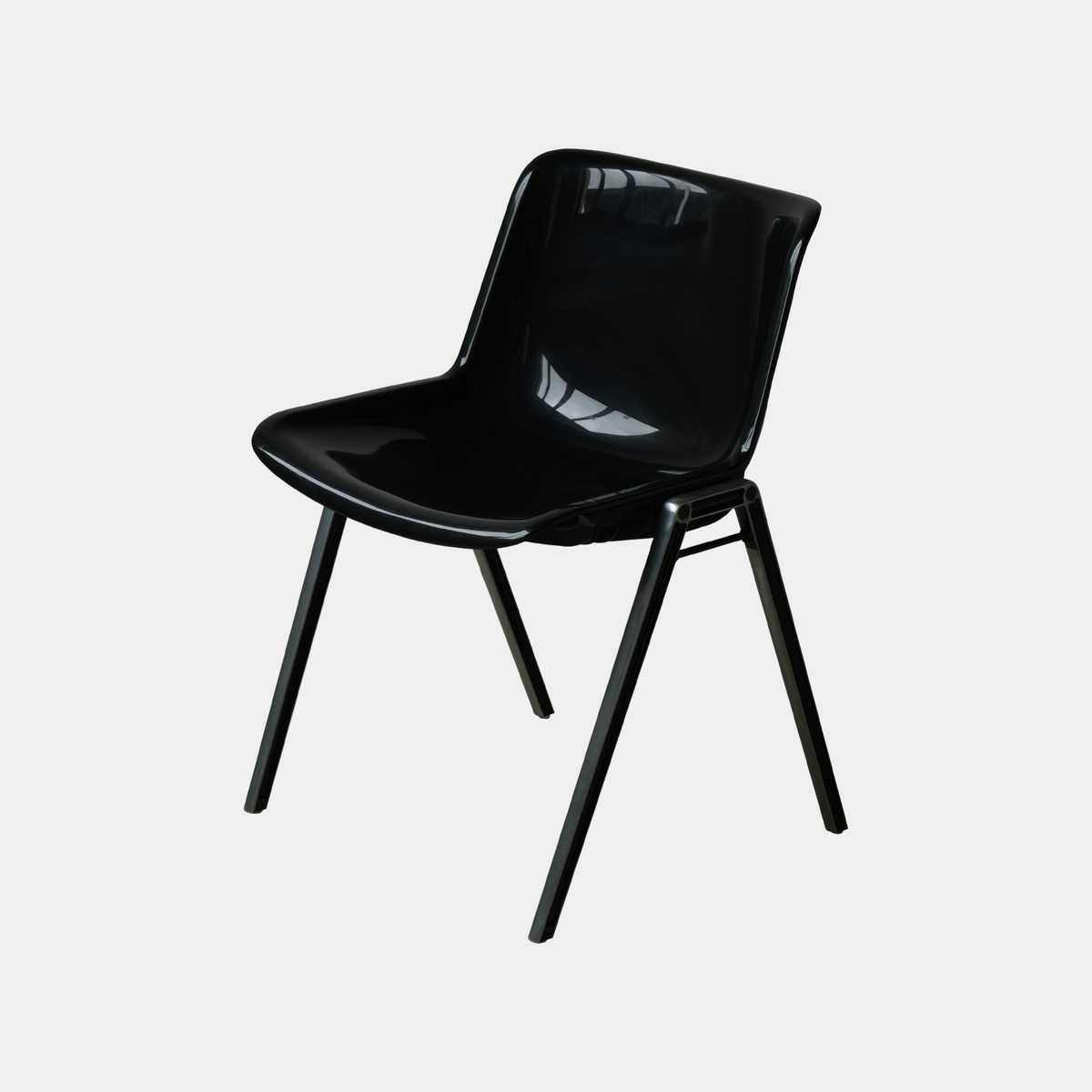 A modern black plastic dining chair with a glossy finish and four angled metal legs, shown against a plain light gray background.