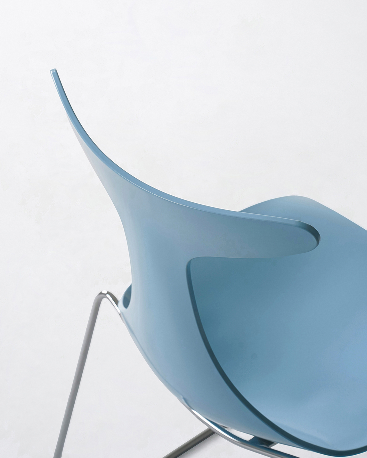 A close-up of a light blue molded plastic chair back and seat with a chrome metal leg base, shown against a plain white background.